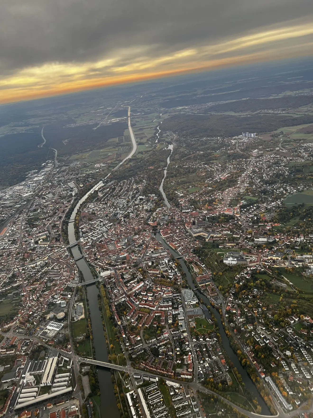 Stadt mit Fluss und Kanal aus der Luft im warmen Abendlicht, Straßen ziehen sich durch die Altstadt
