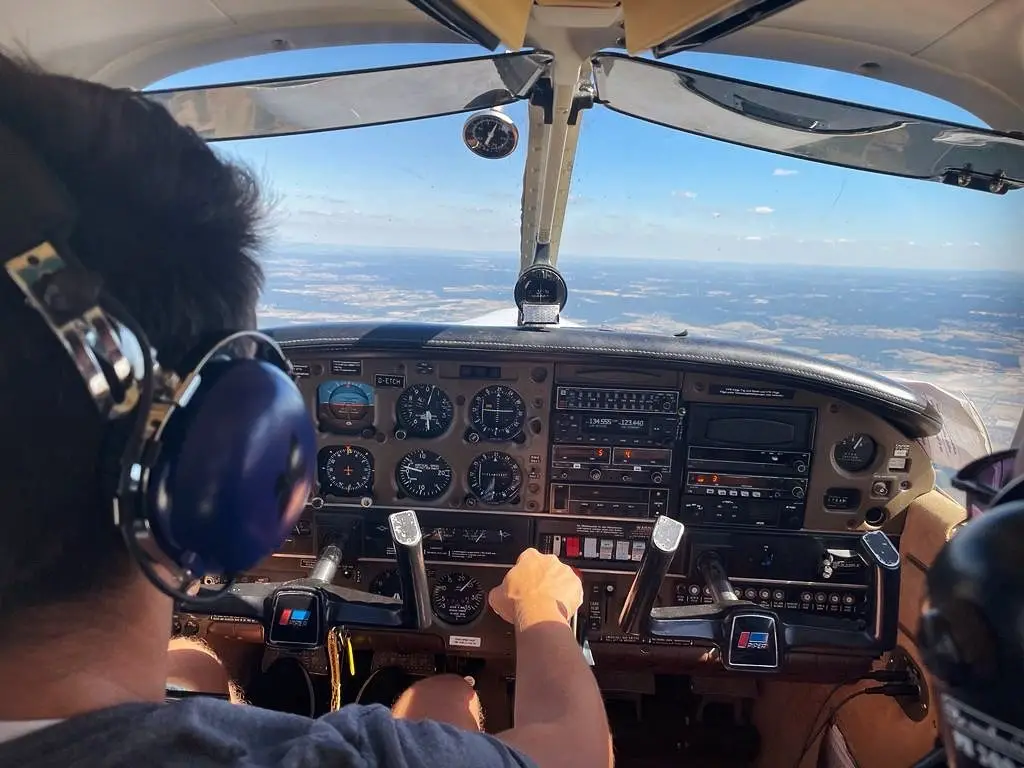 Blick vom rechten Sitz auf den Piloten am Steuer, davor das Instrumentenbrett und der Horizont